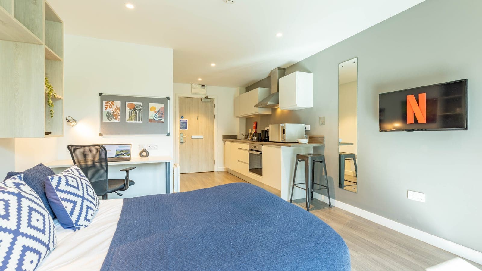 A studio at ABeleven seen from the bed, with the desk, television and kitchen beyond